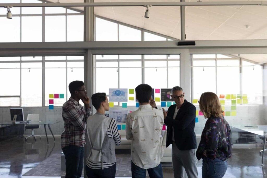 Team discussing collaboration strategies in a modern workspace with post-it notes.